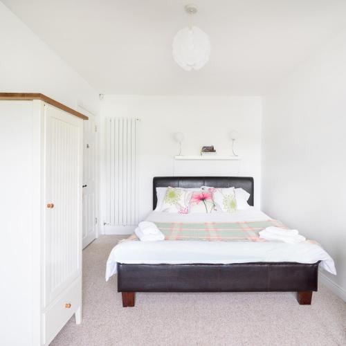 a bedroom with a large bed with white walls at Willow House Bed & Breakfast and Orchard Studios Self Catering in Limavady