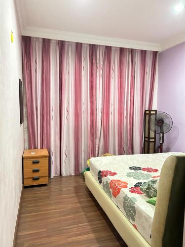 山打根的住宿－BC Homestay，一间卧室配有床、梳妆台和粉红色窗帘