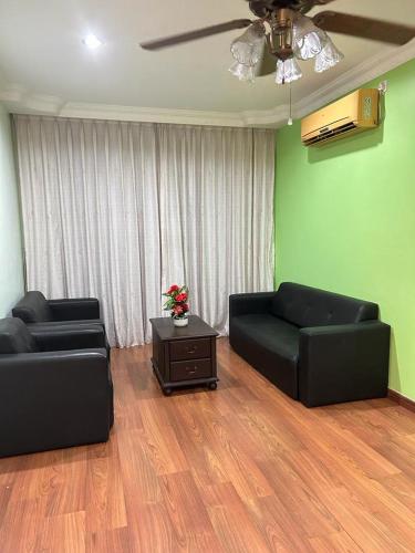 a living room with two black couches and a table at BC Homestay in Sandakan