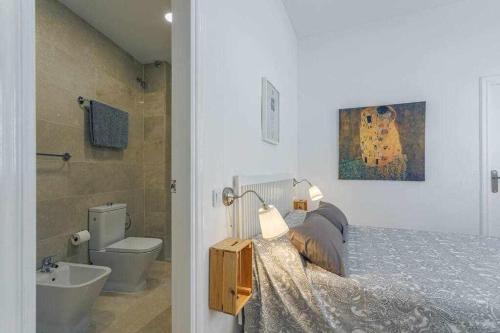 ein Schlafzimmer mit einem Bett und ein Badezimmer mit einem Waschbecken in der Unterkunft Santa Cruz Parking incluido in Sevilla