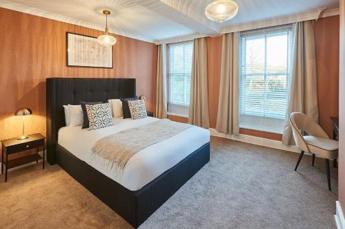 een slaapkamer met een bed, een stoel en ramen bij Host & Stay - Silton Hall in Nether Silton