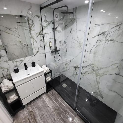 a bathroom with a marble shower and a sink at Nandos Apartement in Costa da Caparica