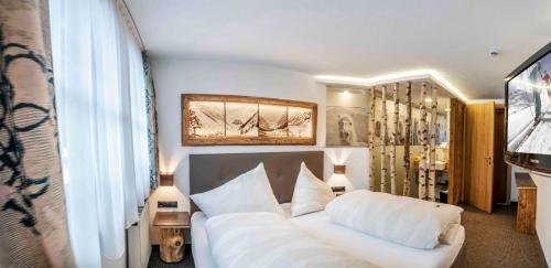 a bedroom with a white bed and a television at Almhof-Reithof Pitztal in Sankt Leonhard im Pitztal
