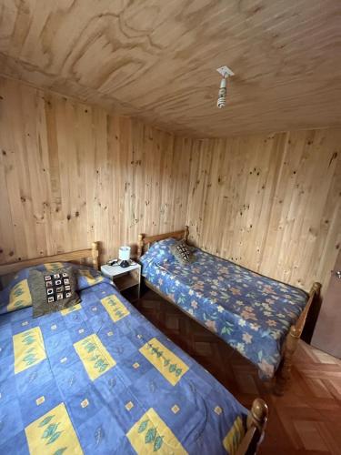 - 2 lits dans une chambre dotée de murs en bois dans l'établissement Cabañas akrilu, à Puchuncaví
