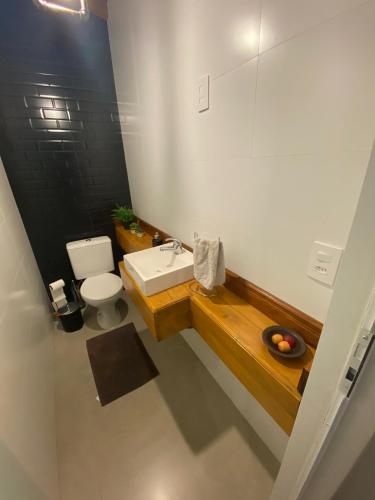 a bathroom with a white toilet and a sink at Casa Temporada in Camboriú