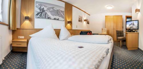 a hotel room with two beds and a desk at Almhof-Reithof Pitztal in Sankt Leonhard im Pitztal