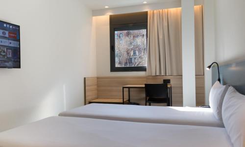a room with a bed and a desk and a table at Hotel Sant Pau in Barcelona