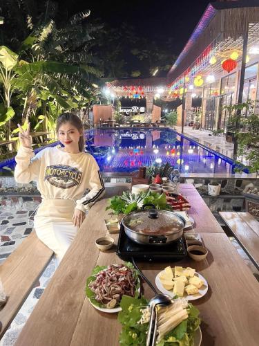 a woman is sitting at a table with food at Ninh Binh Royal Homestay in Ninh Binh