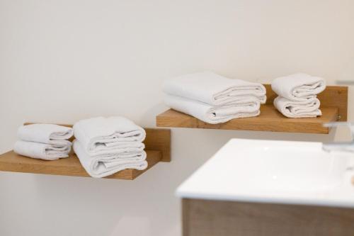 a stack of towels on wooden shelves in a bathroom at Hotel Alaïa in Ascain