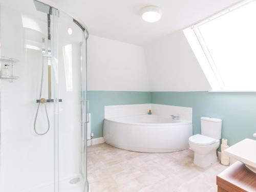 a bathroom with a bath tub and a toilet at Chauffeur's Cottage with Hot Tub in Cray