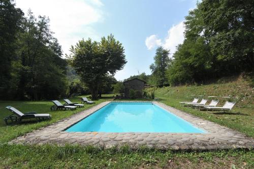a swimming pool with chaises and chairs in a yard at Il Vecchio Mulino in Coreglia Antelminelli