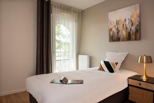 - une chambre avec un grand lit blanc et une fenêtre dans l'établissement Résidence Les Boréales, à Rouen