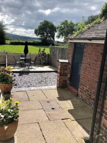a brick house with a patio with a table and chairs at Quaint house in a beautiful rural setting in Froghall