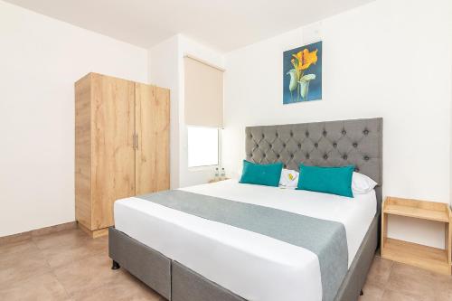 a bedroom with a large white bed with blue pillows at Casa Flor Hostel & Drinks in Ríohacha