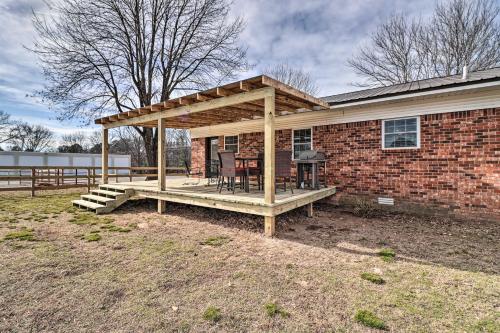 a covered deck with a grill in front of a brick house at Greers Ferry Home on 40 Acres quarter Mi to Lake! in Fairfield Bay