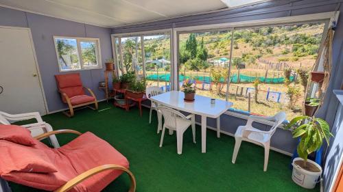 a room with a table and chairs and a large window at Cabaña el Coirón in Cochrane