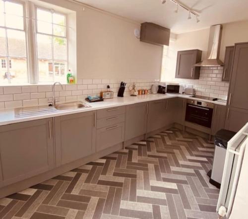 a kitchen with white cabinets and a checkered floor at Cosy Bungalow with a view in Lincoln