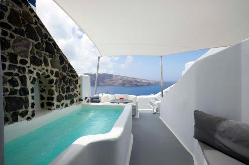 a hot tub in a white room with a view of the ocean at Marizan Caves & Villas in Oia