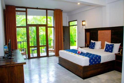 a bedroom with a bed and a television and a balcony at Manike Lodge Habarana in Habarana