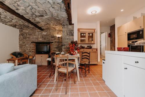 eine Küche und ein Wohnzimmer mit einem Tisch und einer Steinmauer in der Unterkunft Tiny stone in Maredret
