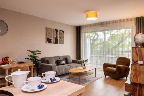 a living room with a couch and a table at Les Boréales - Appart'hotel & Restaurant in Rouen