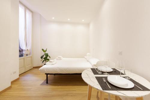 Top Accommodations in the Heart of Milano! في ميلانو: غرفة نوم بيضاء مع سرير وطاولة