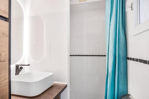 baño con lavabo blanco y cortina de ducha azul en Chabine - avec terrasse, en Martigues