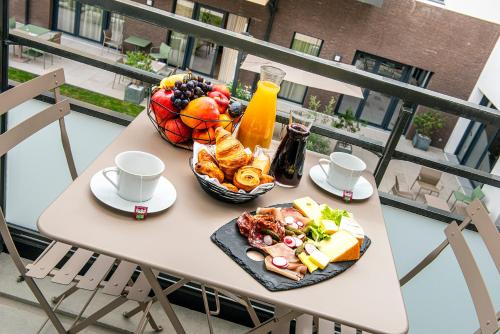a table with a bowl of food and a bowl of fruit at Les Boréales - Appart'hotel & Restaurant in Rouen