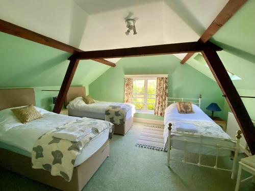 a attic room with two beds and a window at Stable Cottage Peaceful Stunning Retreat near Bath in Upavon