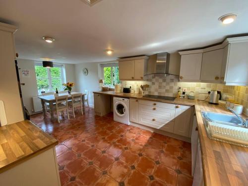 a kitchen with white cabinets and a red tile floor at Stable Cottage Peaceful Stunning Retreat near Bath in Upavon
