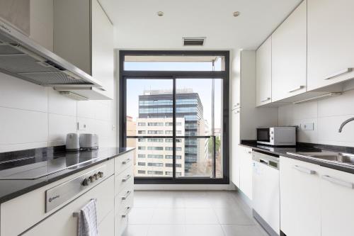 a kitchen with white cabinets and a large window at ChicStays Apartment Vila Olímpica in Barcelona
