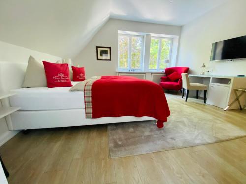 Schlafzimmer mit einem Bett mit einer roten Decke und einem Schreibtisch in der Unterkunft Fürst Bismarck Mühle in Aumühle
