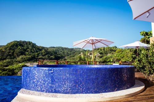 Hotel El Copal في مازونتي: طاولة زرقاء مع كراسي ومظلات بجوار الماء