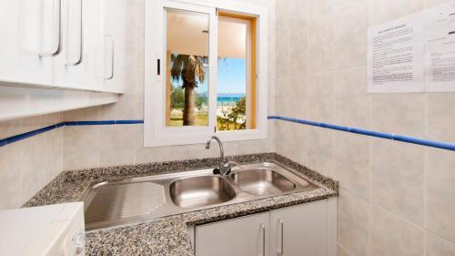 uma cozinha com um lavatório de aço inoxidável e uma janela em SUN OF THE BAY em Alcudia