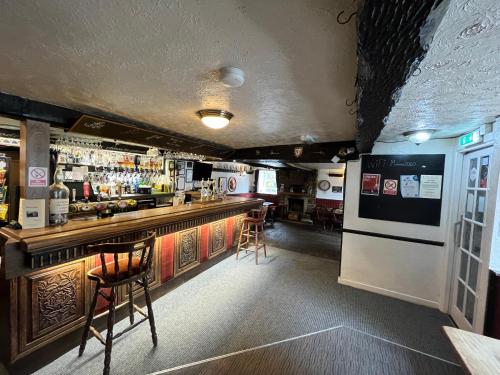 eine Bar in einem Restaurant mit einer Theke und Stühlen in der Unterkunft Masons Arms in Skipton