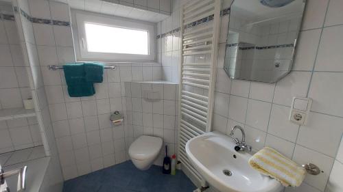 ein weißes Bad mit einem Waschbecken und einem WC in der Unterkunft Seevilla Wietjes Whg 1 in Baltrum