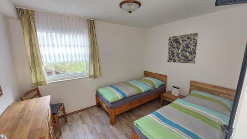 1 Schlafzimmer mit 2 Betten, einem Tisch und einem Fenster in der Unterkunft Seevilla Wietjes Whg 1 in Baltrum
