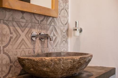 a bathroom with a stone sink and a mirror at BOHO Bohemian Boutique Hotel in Willemstad