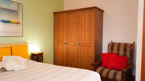 een slaapkamer met een bed, een stoel en een kast bij Panoramic lake view home's Giulia in Casasco Intelvi