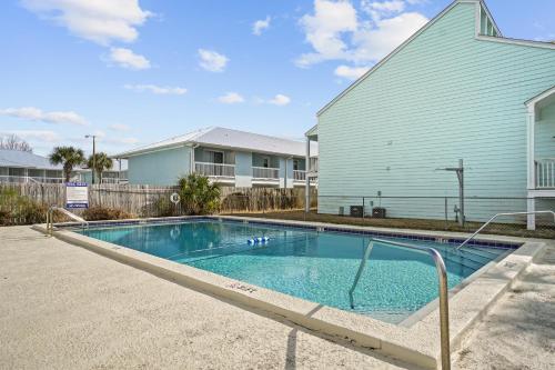 a swimming pool in front of a blue house at Southwind by Panhandle Getaways in Panama City Beach