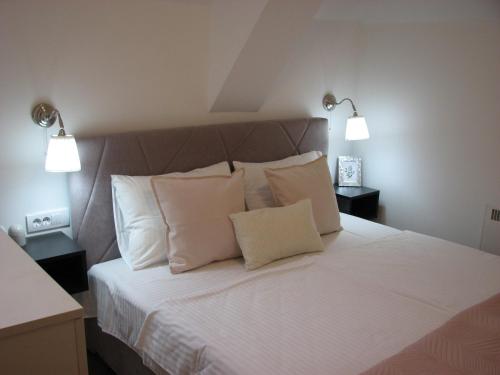 a bedroom with a bed with white sheets and pillows at B&S Apartments in Zlatibor