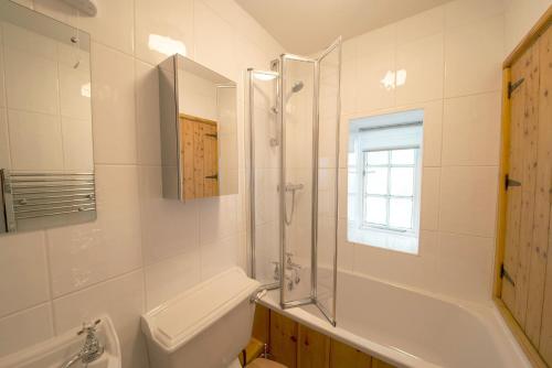 a bathroom with a shower and a toilet and a sink at Old Quarry Cottage Coniston in Coniston