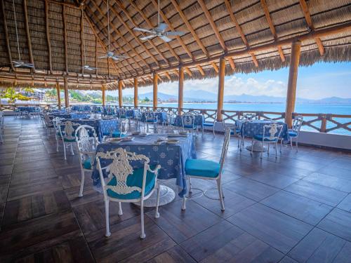 a restaurant with blue tables and chairs and the ocean at Las Hadas by Brisas in Manzanillo