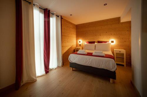 a bedroom with a bed and two large windows at Hôtel Restaurant Le Madame in La Ferrière