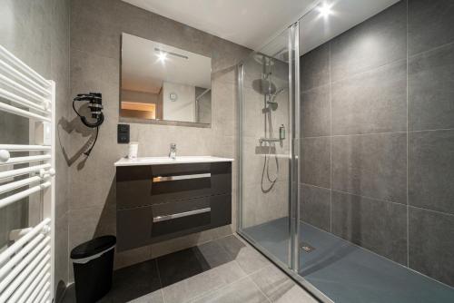 uma casa de banho com um chuveiro, um lavatório e um espelho. em Hôtel Restaurant Le Madame em La Ferrière