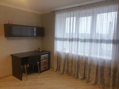 a bedroom with a desk and a window with curtains at Apartament Vasilya Porika 48 Street Vinnitsya in Vinnytsya