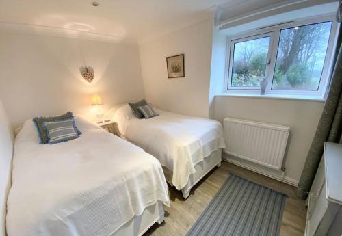 a bedroom with two beds and a window at Secluded Escape near Salcombe - Newhouse Barn. in Malborough