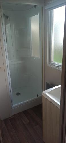 une salle de bain blanche avec une douche et un lavabo dans l'établissement MOBIL-HOME Parc des Allais, à Trogues