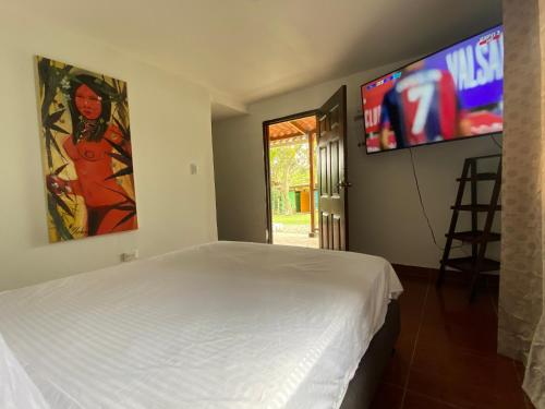 a bedroom with a white bed and a flat screen tv at MAGICA CABAÑA EN MEDIO DE LA NATURALEZA in Armenia