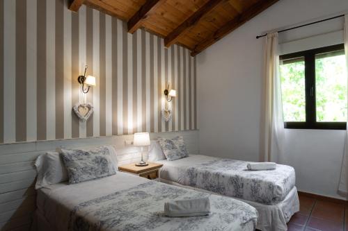 a bedroom with two beds and a lamp and a window at El Manantial Del Fresno Casas Rurales En Hervás in Hervás